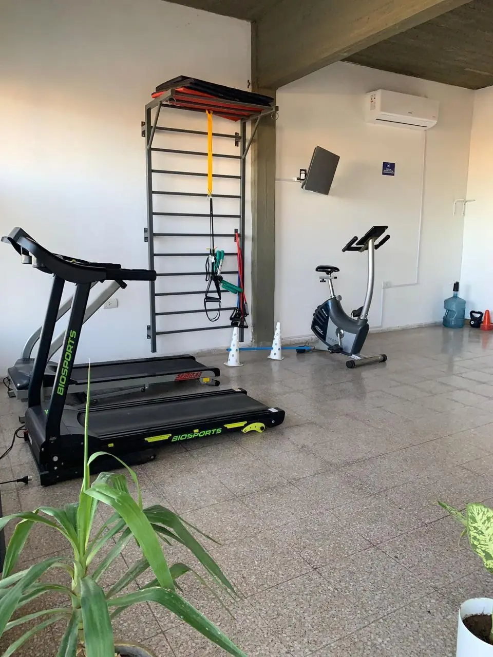 Sala de entrenamiento de Mandra con cintas, bicicleta fija, espaldar y elementos de entrenamiento